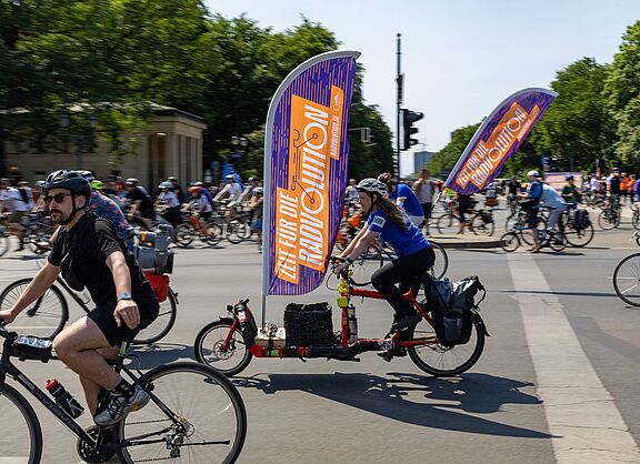 ADFC-Sternfahrt Berlin 2023 Viele Menschen auf Fahrrädern. An einem Rad befindet sich eine große Fahne mit dem Wort "Radvolution" darauf.