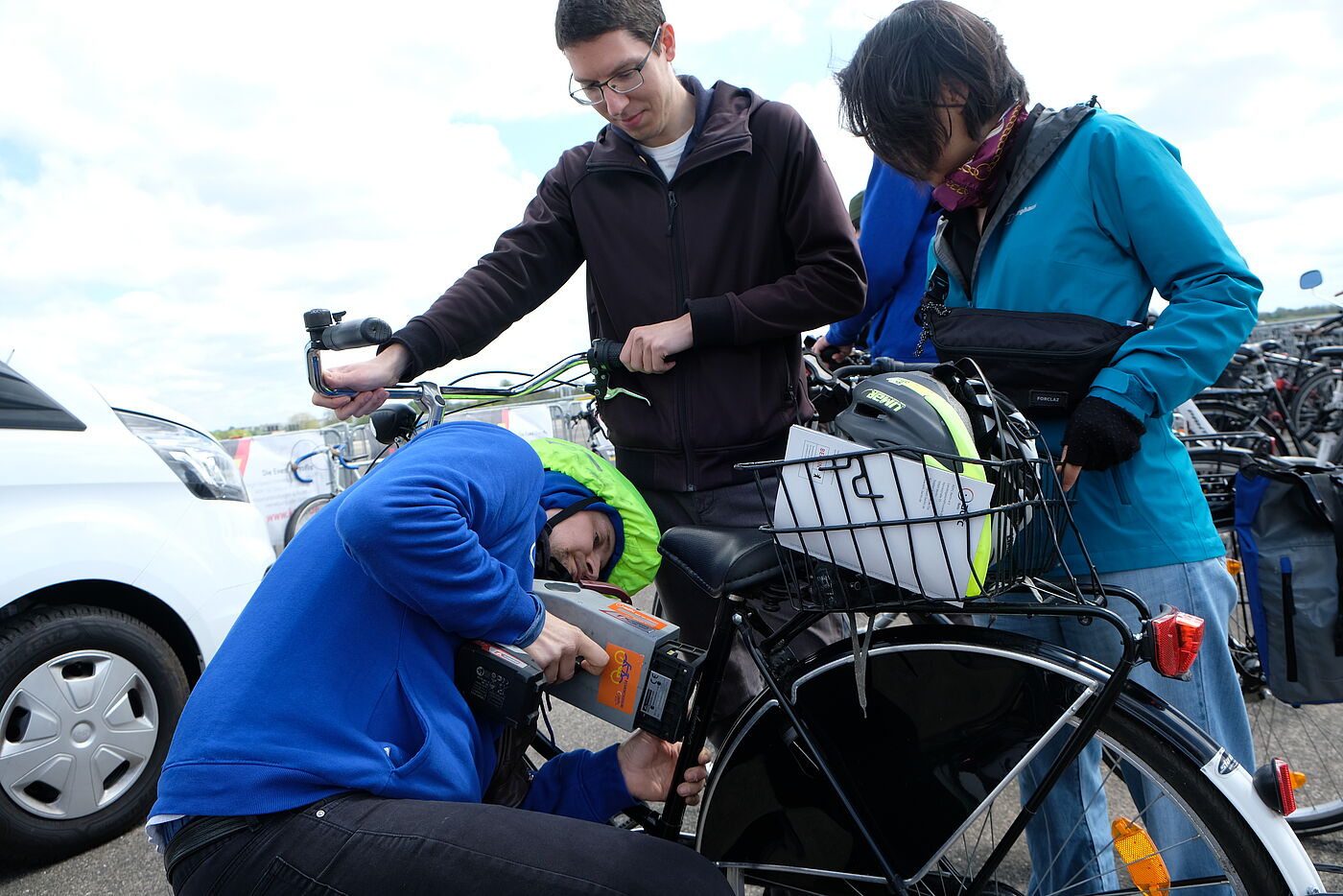 Mechaniker codiert Fahrrad während Frau und Mann das Fahrrad festhalten