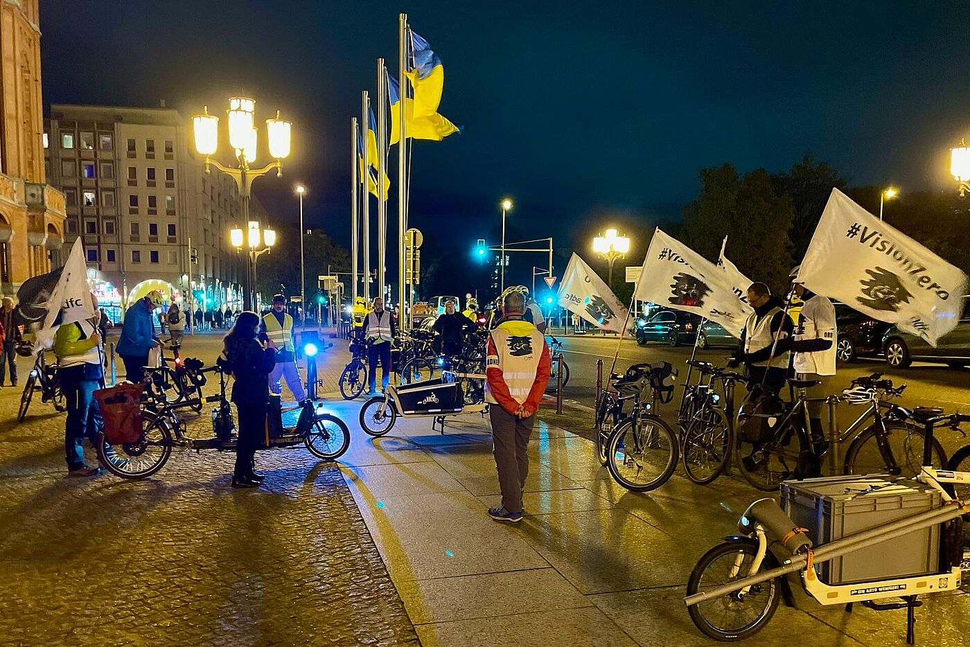 Menschen stehen mit Fahrrädern und weißen Vision Zero Fahnen vor dem Roten Rathaus bei einer Kundgebung