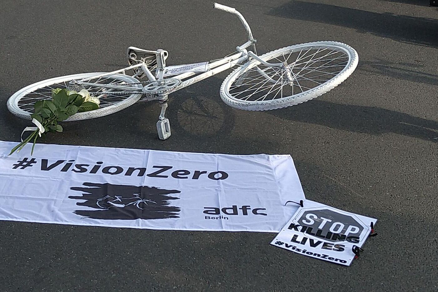 weißes Fahrrad auf dem Boden, Vision Zero Banner darunter