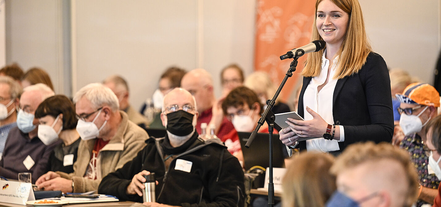 Rebecca Peters steht zwischen den sitzenden Delegierten