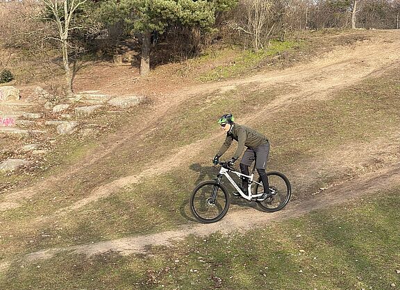 Mountainbiker auf einer Abfahrt im Gelände bei sonnigem Winterwetter. 