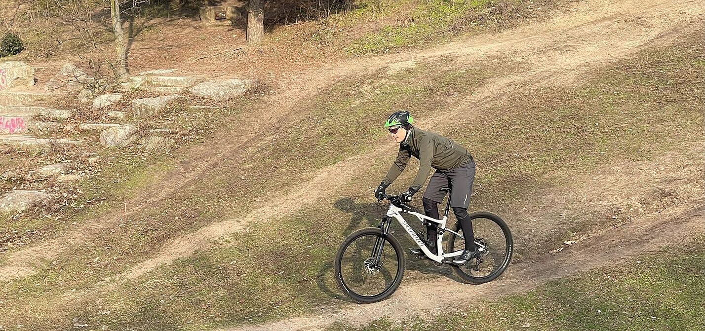 Mountainbiker auf einer Abfahrt im Gelände bei sonnigem Winterwetter. 