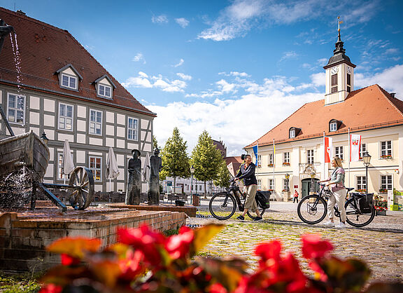 Zwei Frauen mit Fahrrädern auf einem kleinen Marktplatz in einer brandenburgischen kleinen Stadt