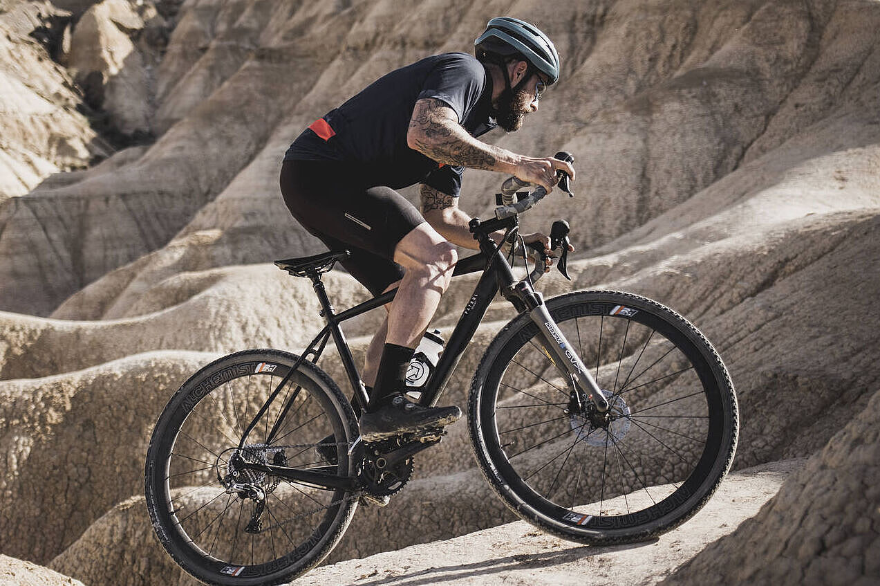 Ein Radfahrer auf einem gefederten Gravelbike. 