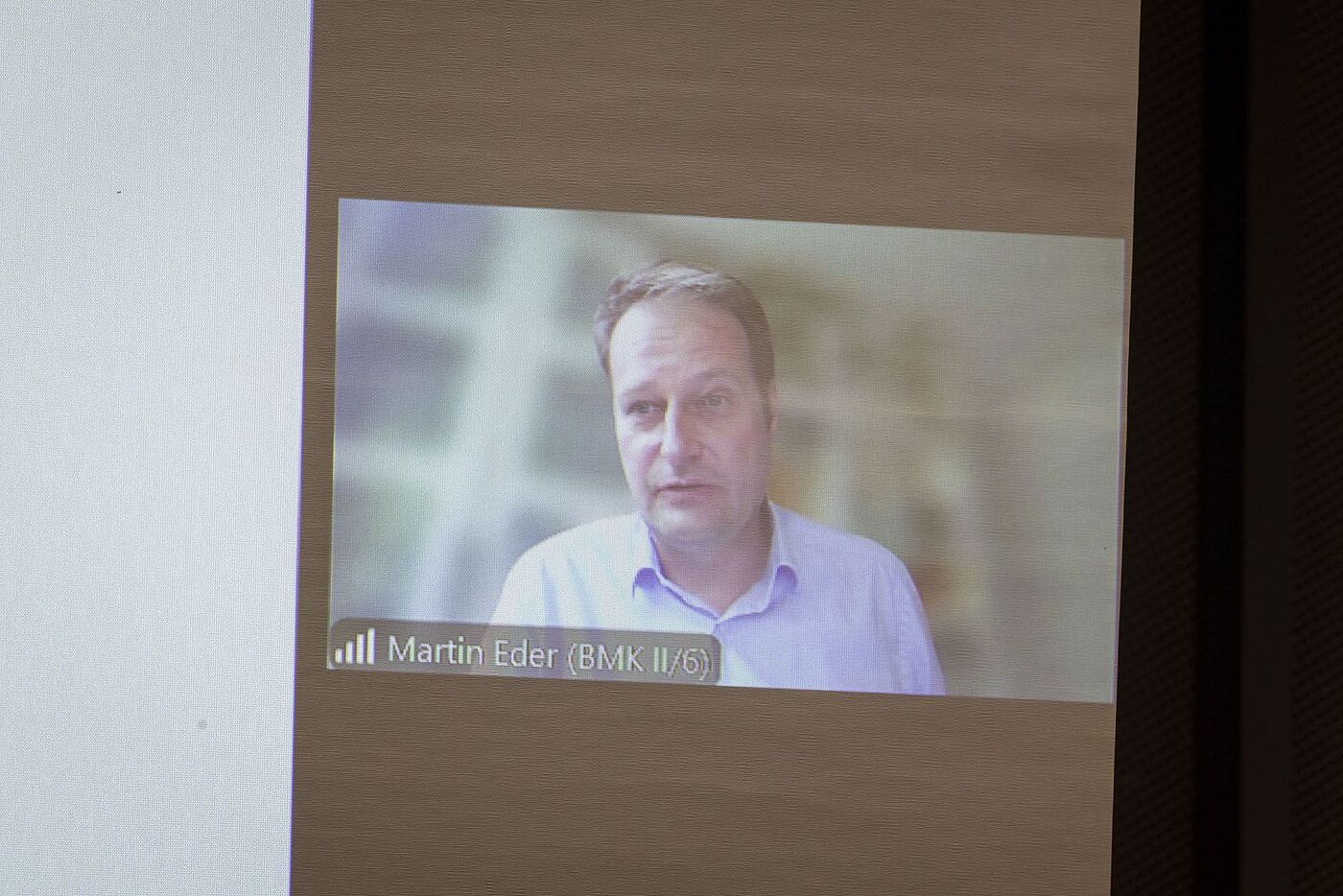 Eine Videoleinwand zeigt Martin Eder aus Österreich, der per Videoübertragung einen Vortrag hält. 