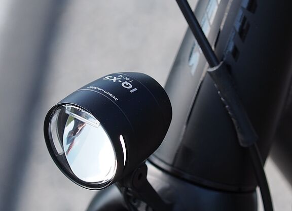 LED-Fahrradscheinwerfer Schwarzer LED-Fahrradscheinwerfer am silbernen Fahrradlenker montiert.