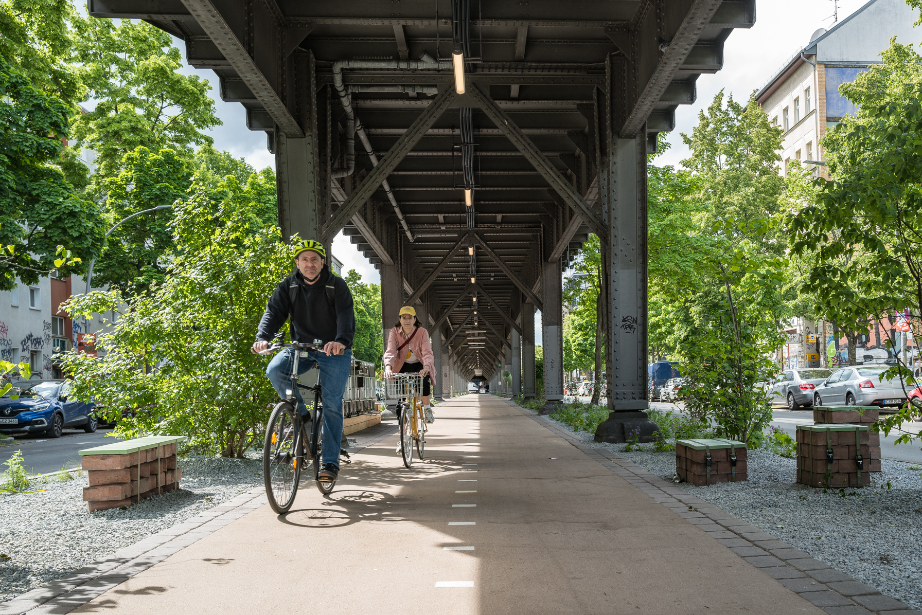 Zwei Radfahrende fahren auf der Teststrecke der Radbahn unter der U-Bahntrasse in Berlin. 