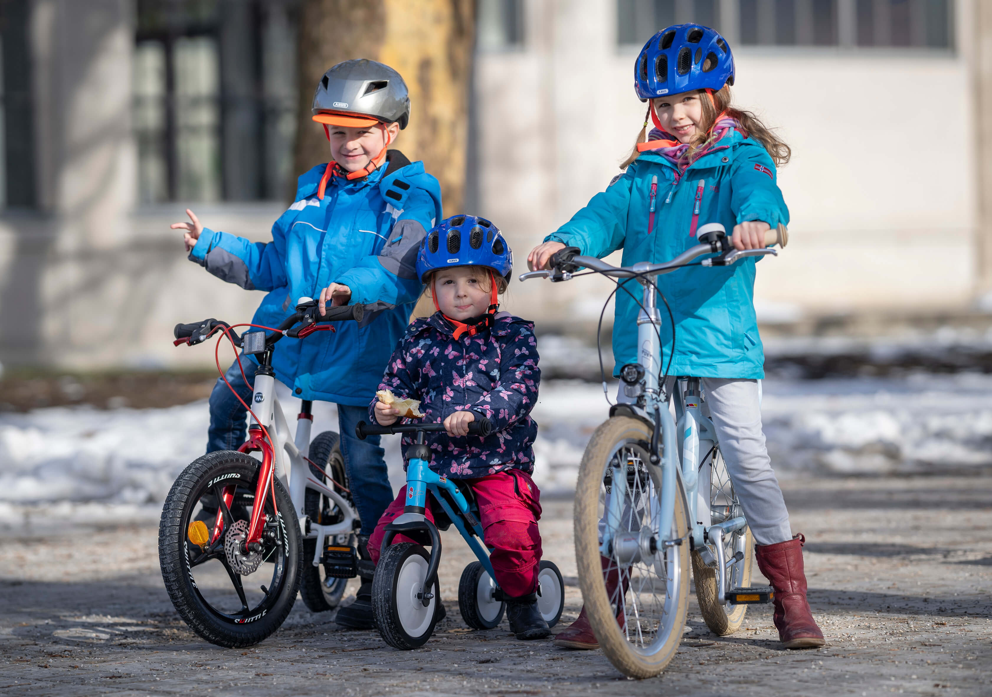 Drei Kinder in unterschiedlichem Alter auf Fahrrädern.